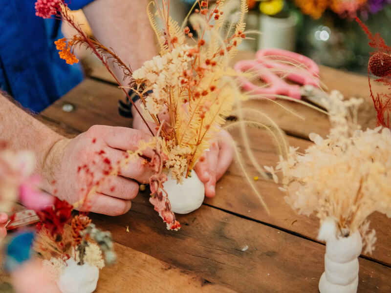 Man's hands holding a miniature dried flower display